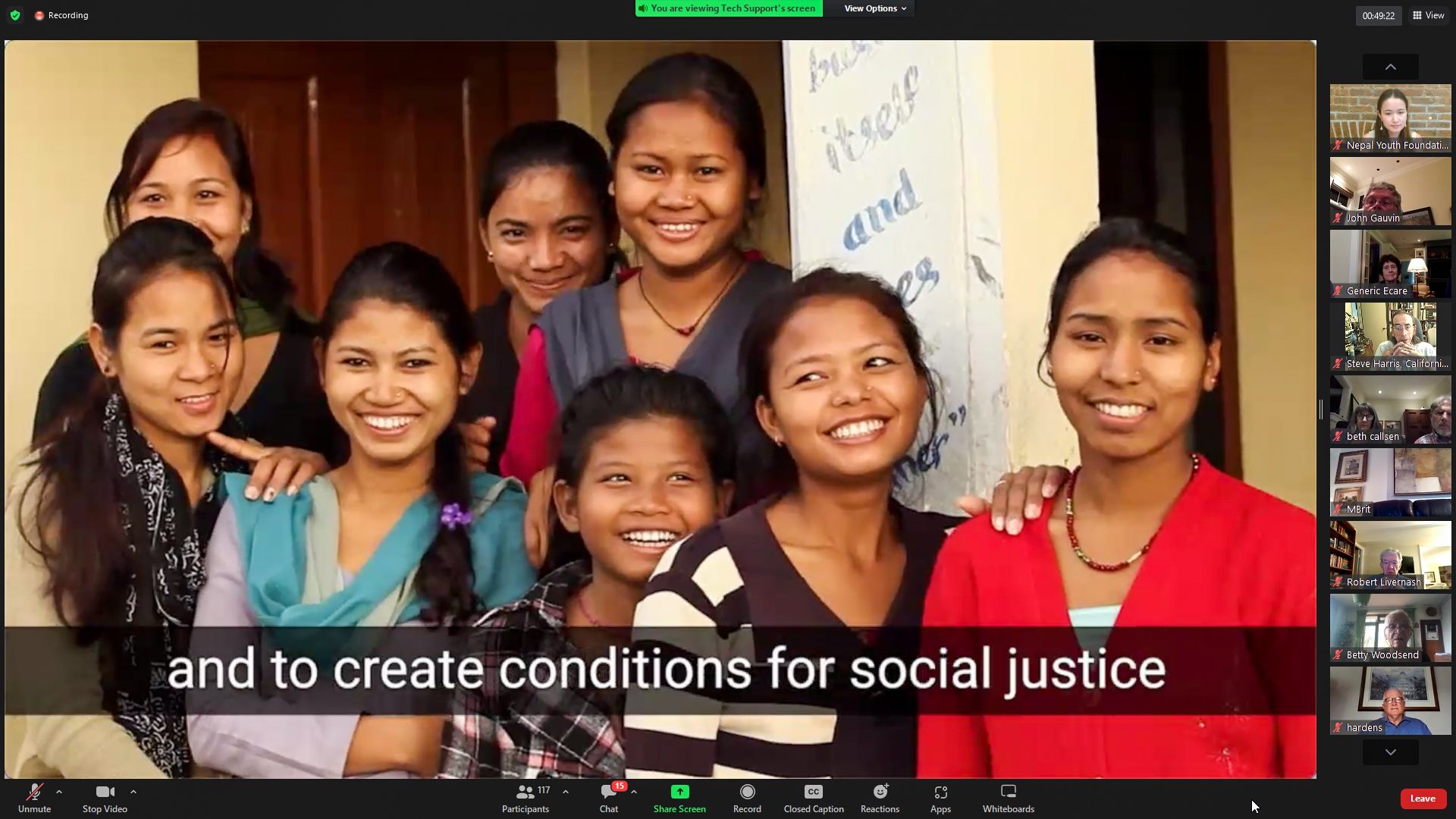 A Zoom screenshot from a video presentation during Founder's Day 2022. A caption along the bottom says, "and to create conditions for social justice". The image is of a group of eight young Nepali women grinning at the camera while standing together with a friendly, familiar energy between them. Their clothes are office casual and blend elements of western and Nepali styles.
